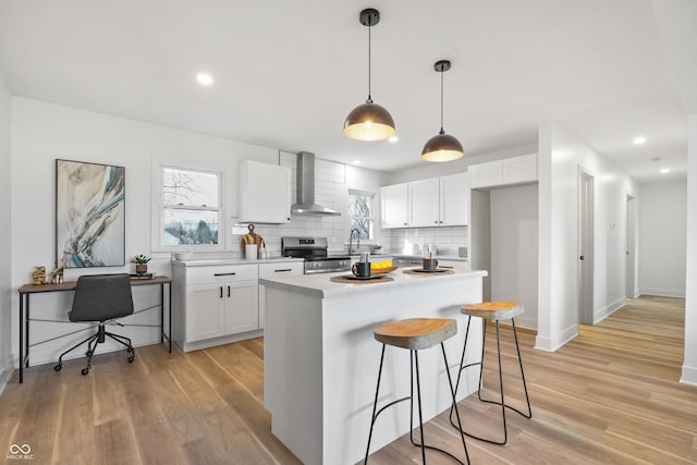 kitchen featuring a kitchen island, pendant lighting, white cabinetry, electric range, and wall chimney range hood