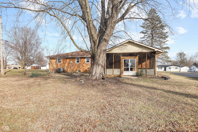 back of house featuring a lawn, a sunroom, and central air condition unit