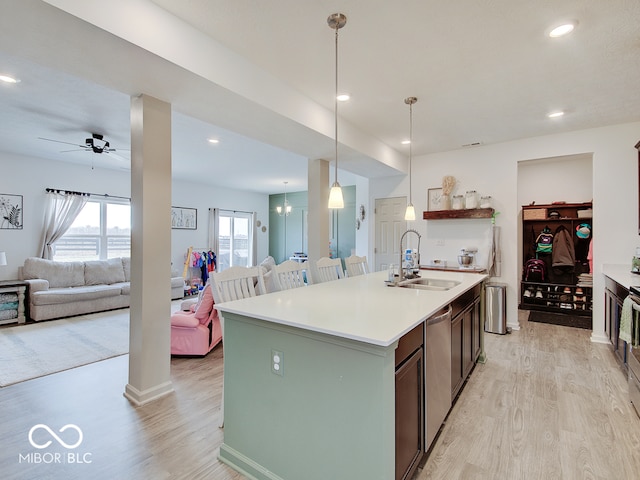 kitchen featuring pendant lighting, sink, light hardwood / wood-style flooring, a center island with sink, and ceiling fan with notable chandelier