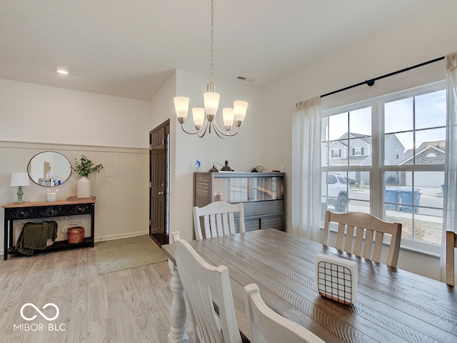 dining space featuring wood-type flooring, plenty of natural light, and a notable chandelier