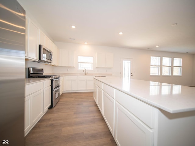 kitchen with a kitchen island, appliances with stainless steel finishes, light wood-type flooring, a sink, and recessed lighting