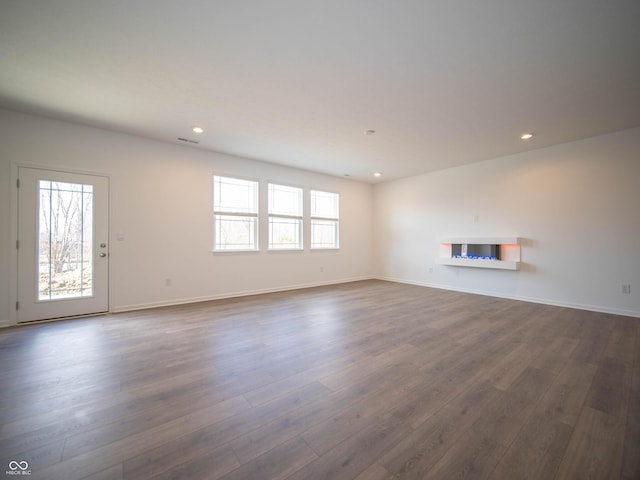 unfurnished living room featuring recessed lighting, a healthy amount of sunlight, and dark wood finished floors