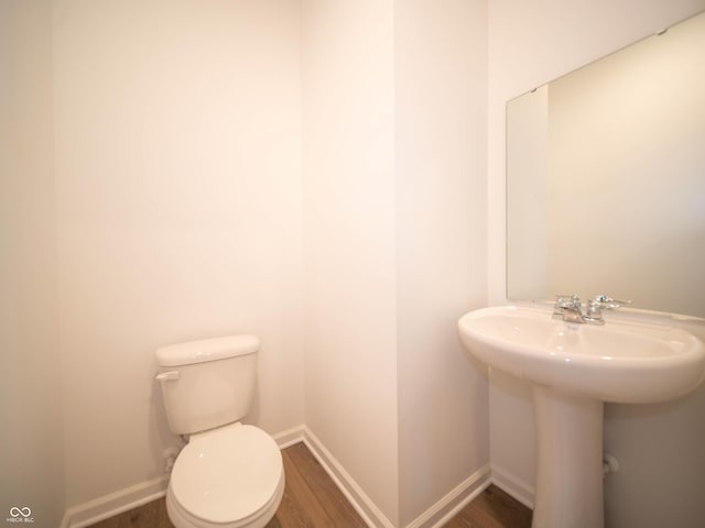 bathroom featuring baseboards, a sink, toilet, and wood finished floors