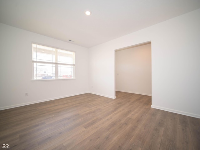 empty room with baseboards, dark wood finished floors, and recessed lighting