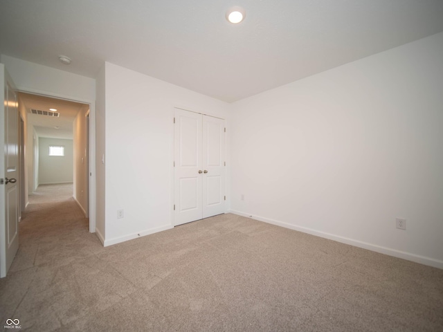 unfurnished bedroom featuring light carpet, a closet, visible vents, and baseboards