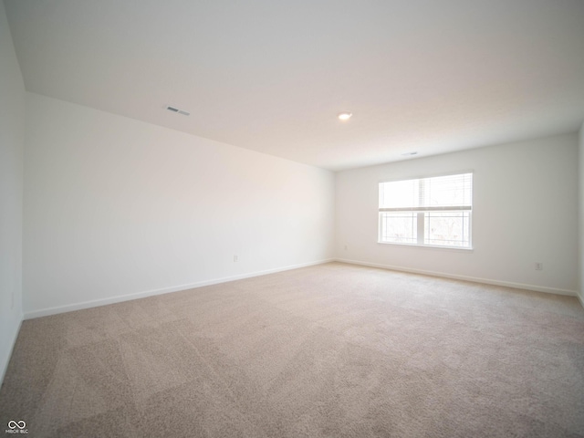 spare room with baseboards, visible vents, and light colored carpet