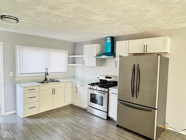 kitchen featuring wall chimney exhaust hood, stainless steel appliances, sink, and white cabinets