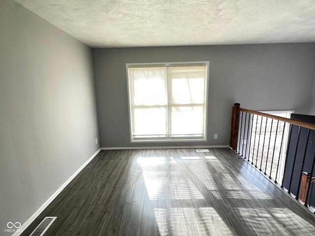 empty room featuring dark wood-type flooring and a textured ceiling