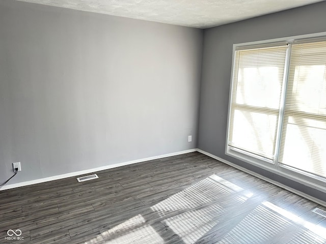 empty room featuring dark wood-type flooring and a textured ceiling