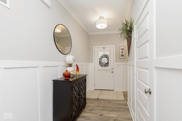 doorway to outside with ornamental molding and light hardwood / wood-style floors