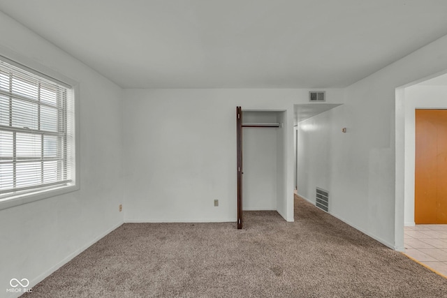 unfurnished bedroom featuring a closet and light carpet