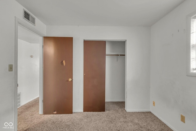 unfurnished bedroom featuring light colored carpet and a closet