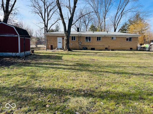 back of property featuring a yard and an outdoor structure