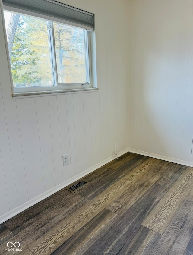 empty room featuring plenty of natural light and dark hardwood / wood-style floors