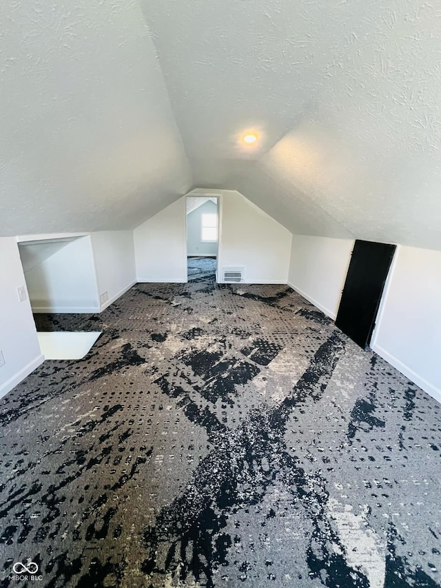 bonus room featuring vaulted ceiling and a textured ceiling