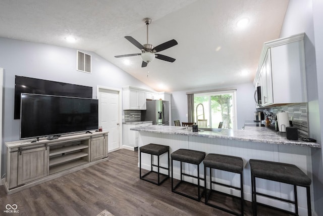 kitchen featuring white cabinetry, a breakfast bar area, kitchen peninsula, stainless steel appliances, and dark wood-type flooring