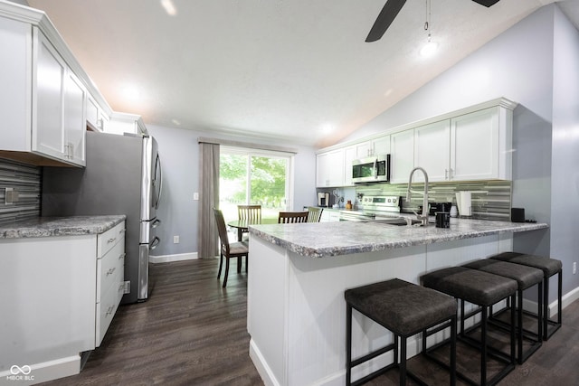 kitchen featuring white cabinetry, appliances with stainless steel finishes, a breakfast bar, and kitchen peninsula