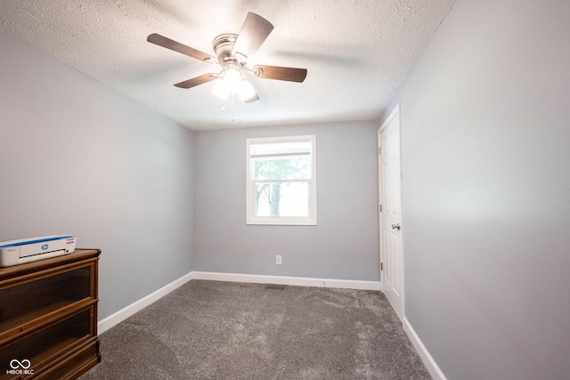 empty room featuring ceiling fan, dark carpet, and a textured ceiling