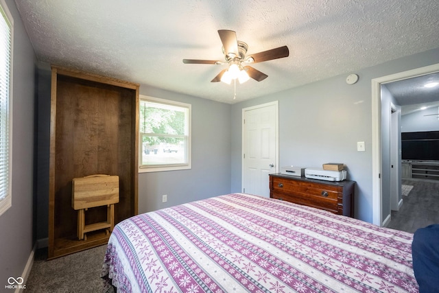 bedroom with dark colored carpet, ceiling fan, and a textured ceiling