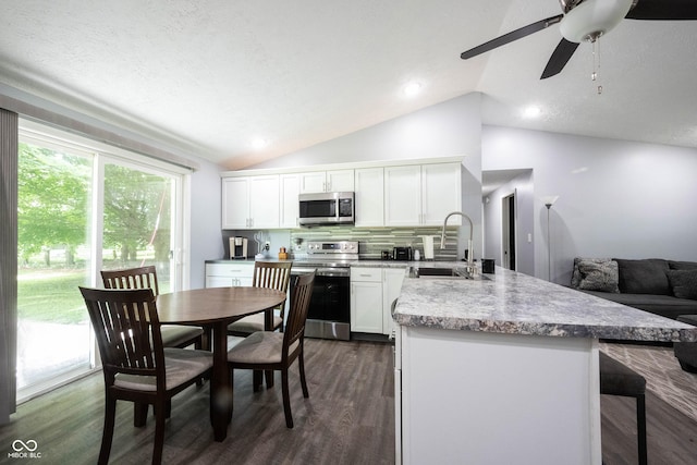 kitchen with vaulted ceiling, stainless steel appliances, sink, and white cabinets