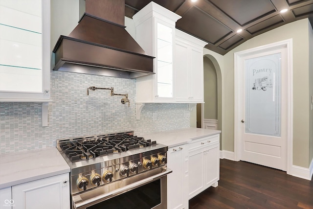 kitchen with light stone counters, dark wood-type flooring, premium range hood, white cabinetry, and stainless steel range