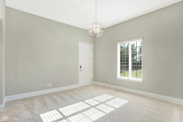 unfurnished room with light carpet, a chandelier, and baseboards