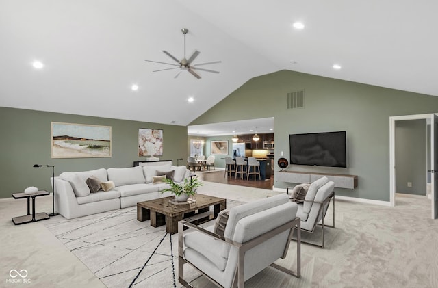 living room with ceiling fan, high vaulted ceiling, light carpet, visible vents, and baseboards