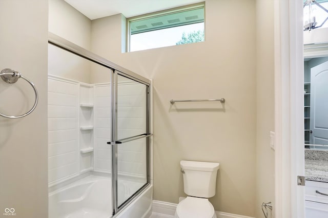 full bath featuring enclosed tub / shower combo, toilet, and baseboards