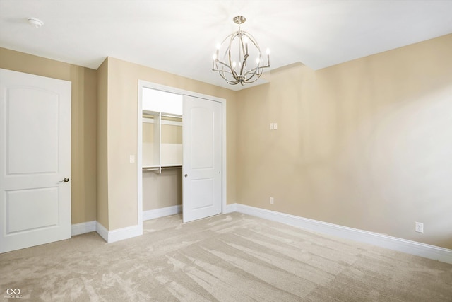 unfurnished bedroom featuring a closet, light colored carpet, baseboards, and an inviting chandelier