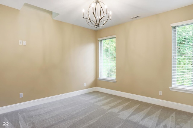 spare room featuring a chandelier, baseboards, visible vents, and light colored carpet