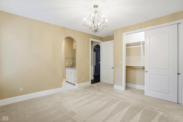 unfurnished bedroom with light carpet, baseboards, arched walkways, and a closet