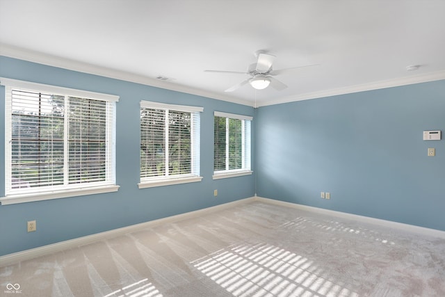 carpeted spare room with crown molding, baseboards, and ceiling fan