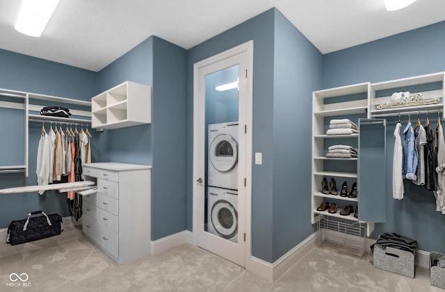 walk in closet with stacked washer / dryer and light colored carpet