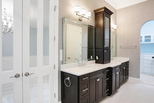 full bathroom with ornamental molding, double vanity, a sink, and wallpapered walls