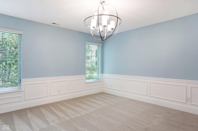 unfurnished room featuring a chandelier, wainscoting, light carpet, and visible vents