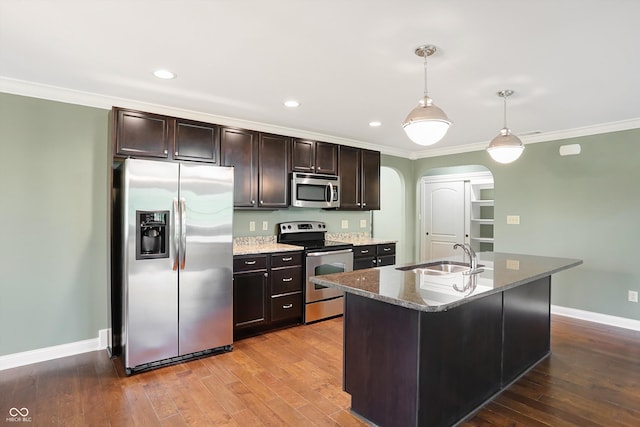 kitchen featuring arched walkways, stainless steel appliances, ornamental molding, a sink, and hardwood / wood-style floors