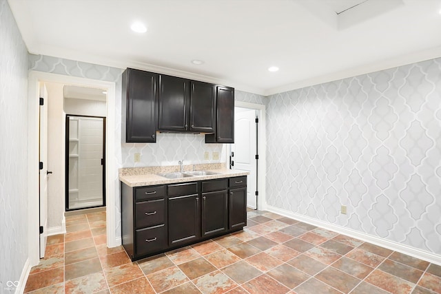 kitchen with wallpapered walls, baseboards, a sink, and recessed lighting