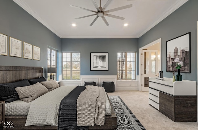 bedroom with a ceiling fan, wainscoting, crown molding, and light carpet