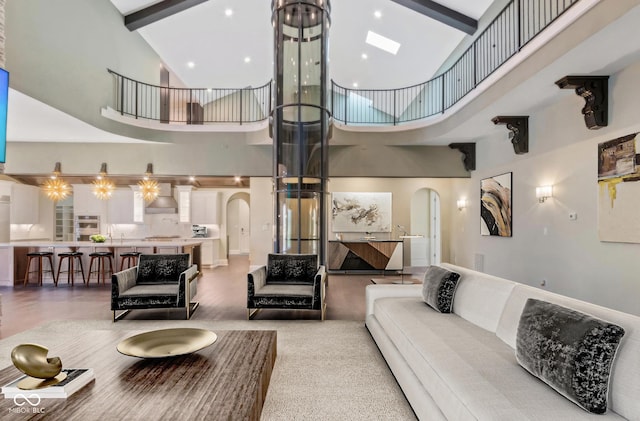 living room with arched walkways, a towering ceiling, beam ceiling, and recessed lighting