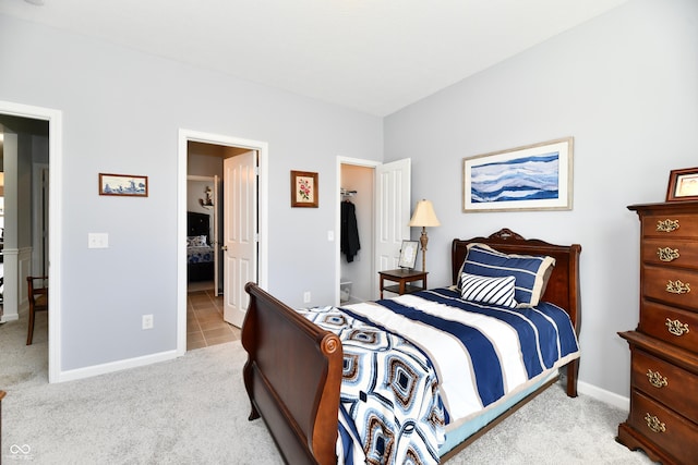 bedroom with light carpet and a walk in closet