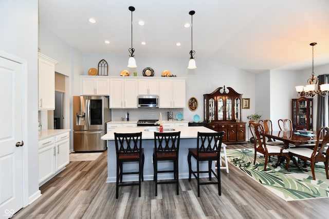 kitchen featuring white cabinetry, stainless steel appliances, and decorative light fixtures