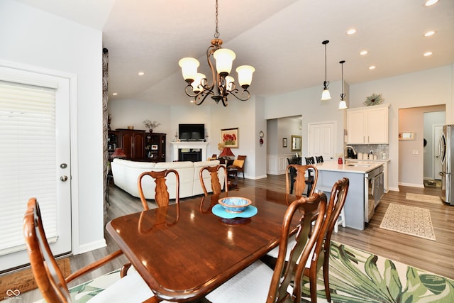 dining room with vaulted ceiling, sink, a notable chandelier, and dark hardwood / wood-style flooring