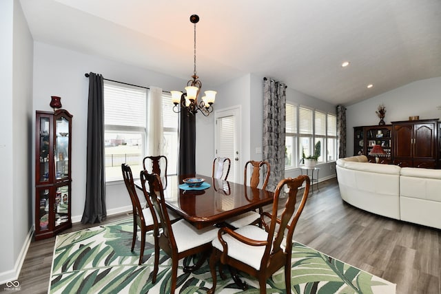 dining area featuring lofted ceiling, hardwood / wood-style floors, and an inviting chandelier