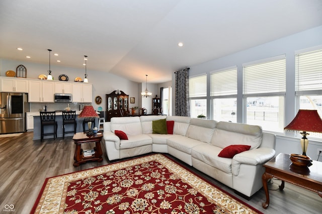 living room featuring lofted ceiling, dark hardwood / wood-style floors, a chandelier, and a wealth of natural light