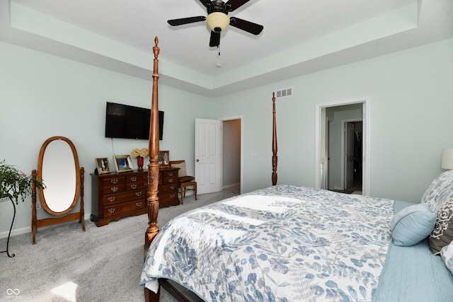 bedroom with light carpet, a raised ceiling, and ceiling fan