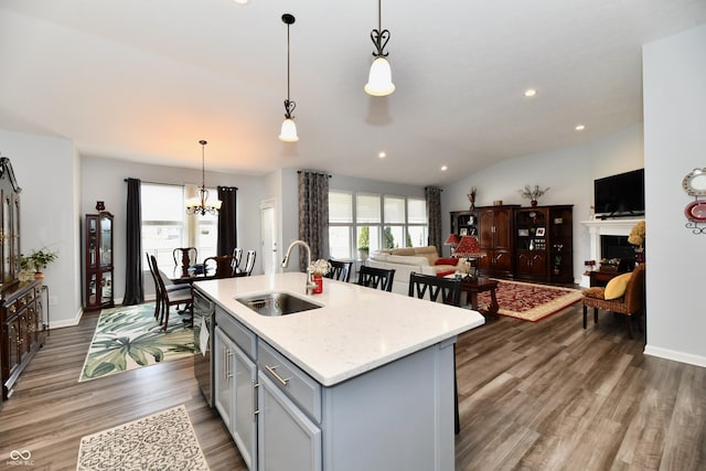 kitchen featuring dark hardwood / wood-style floors, pendant lighting, sink, gray cabinetry, and a kitchen island with sink