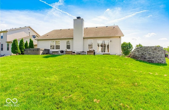 back of property featuring a shingled roof, a chimney, a yard, and a hot tub