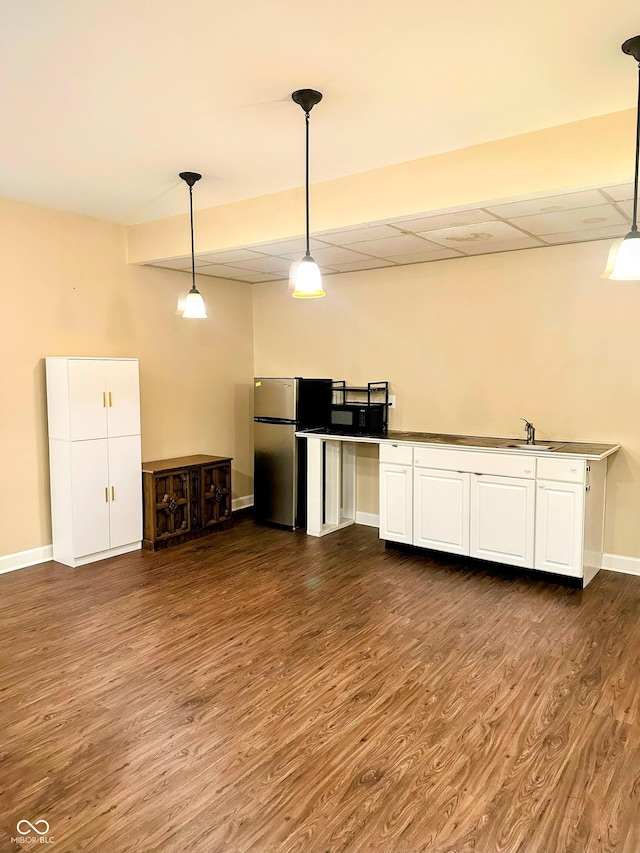 kitchen featuring dark wood-style floors, hanging light fixtures, freestanding refrigerator, white cabinets, and baseboards