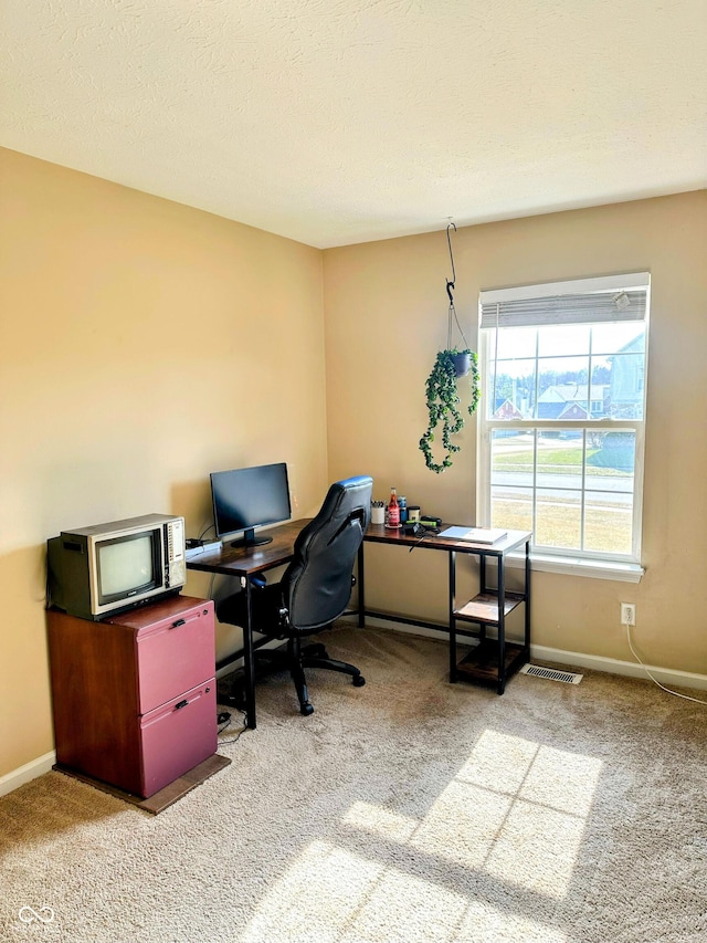 carpeted office space featuring visible vents, baseboards, and a textured ceiling