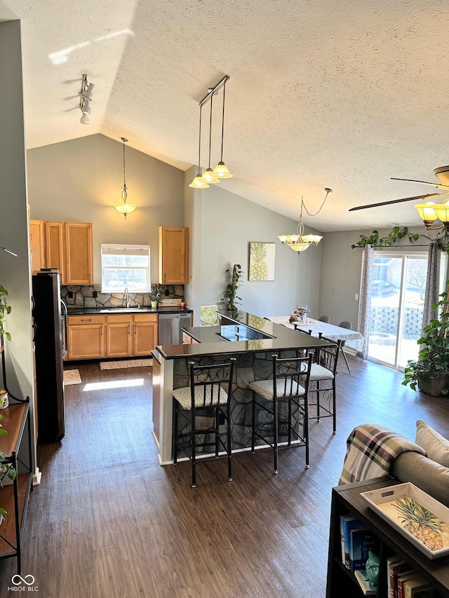 kitchen with dark countertops, appliances with stainless steel finishes, a wealth of natural light, and lofted ceiling